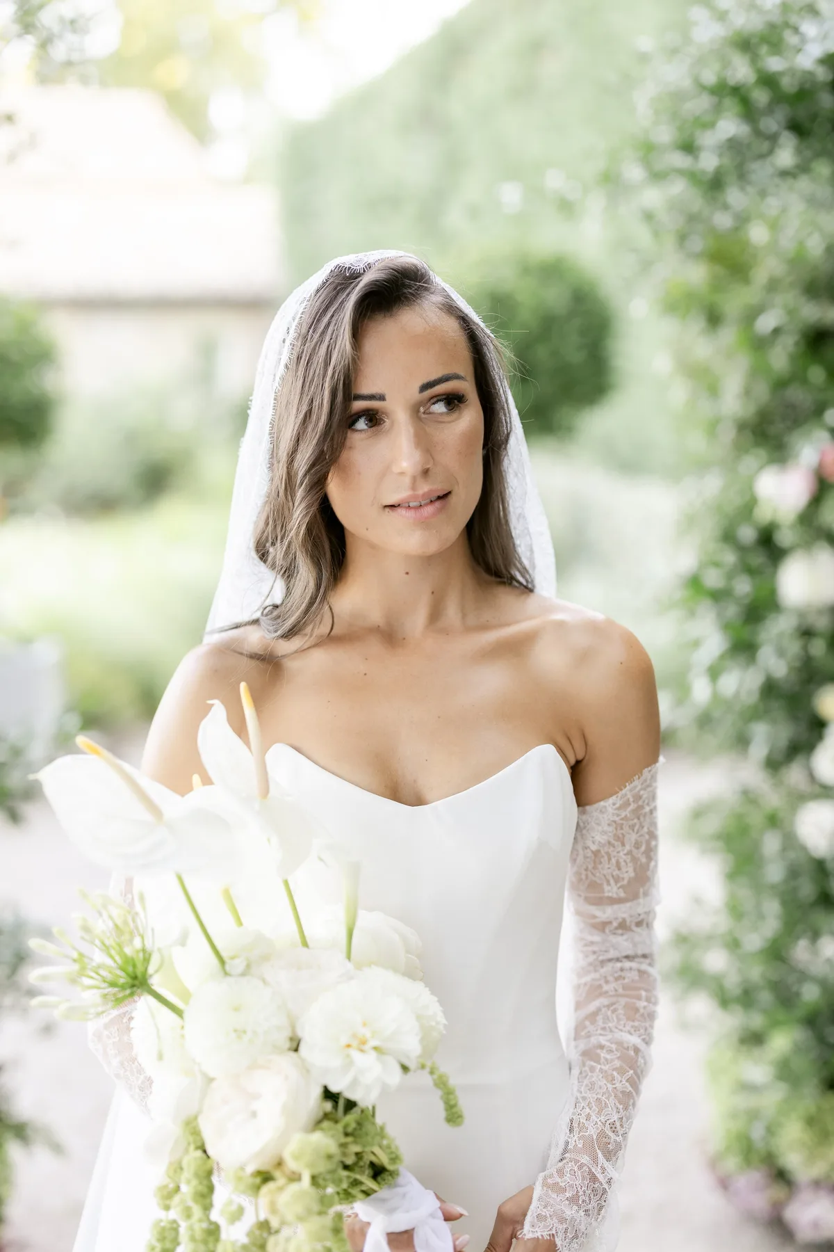 Portrait d'une mariée en voile et manches de dentelle, bouquet d'anthuriums, pour un quiet wedding en Provence
