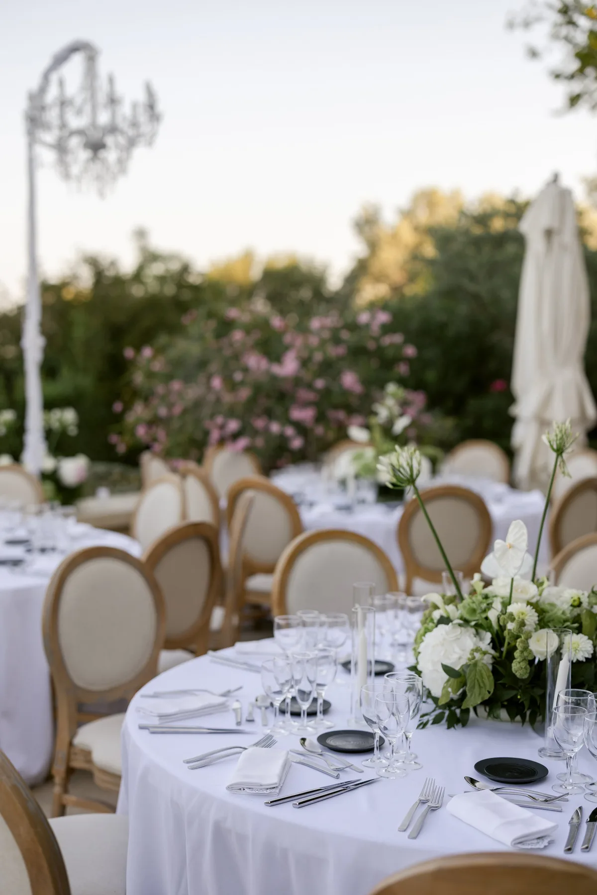 Table ronde soignée aux fleurs blanches, lustre en fond, petite tablée pour un quiet wedding en Provence