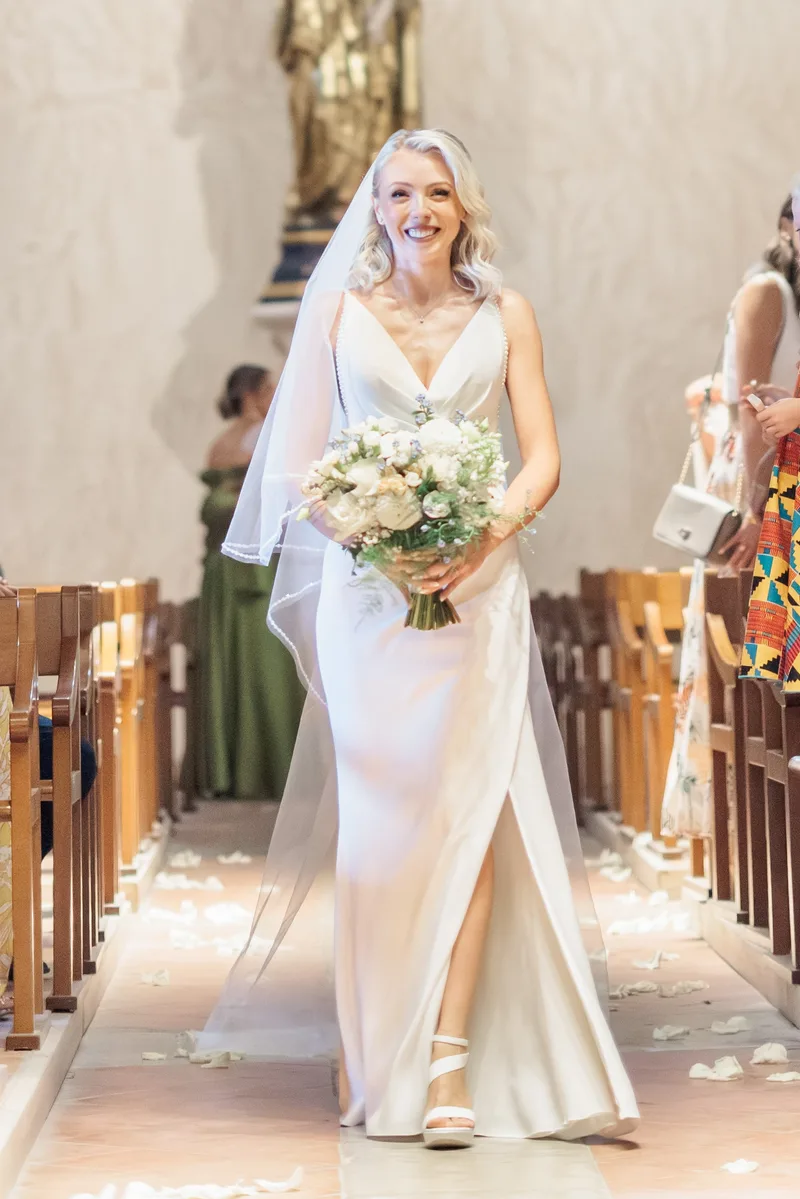 Mariée souriante et bouquet lors du cortège à l'église