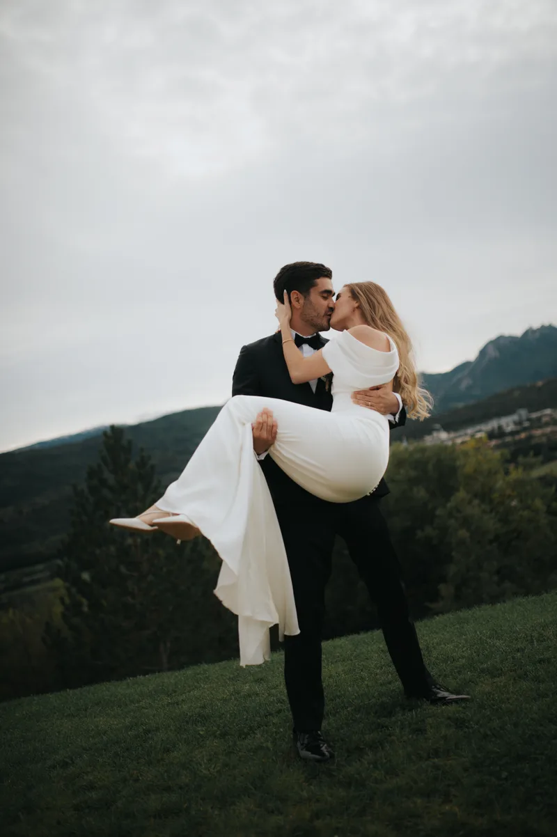 Marié portant la mariée dans ses bras, montagnes en arrière-plan